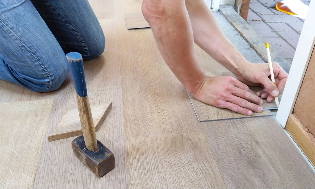 Nexa carpenter marking a hardwood plank during a floor installation
